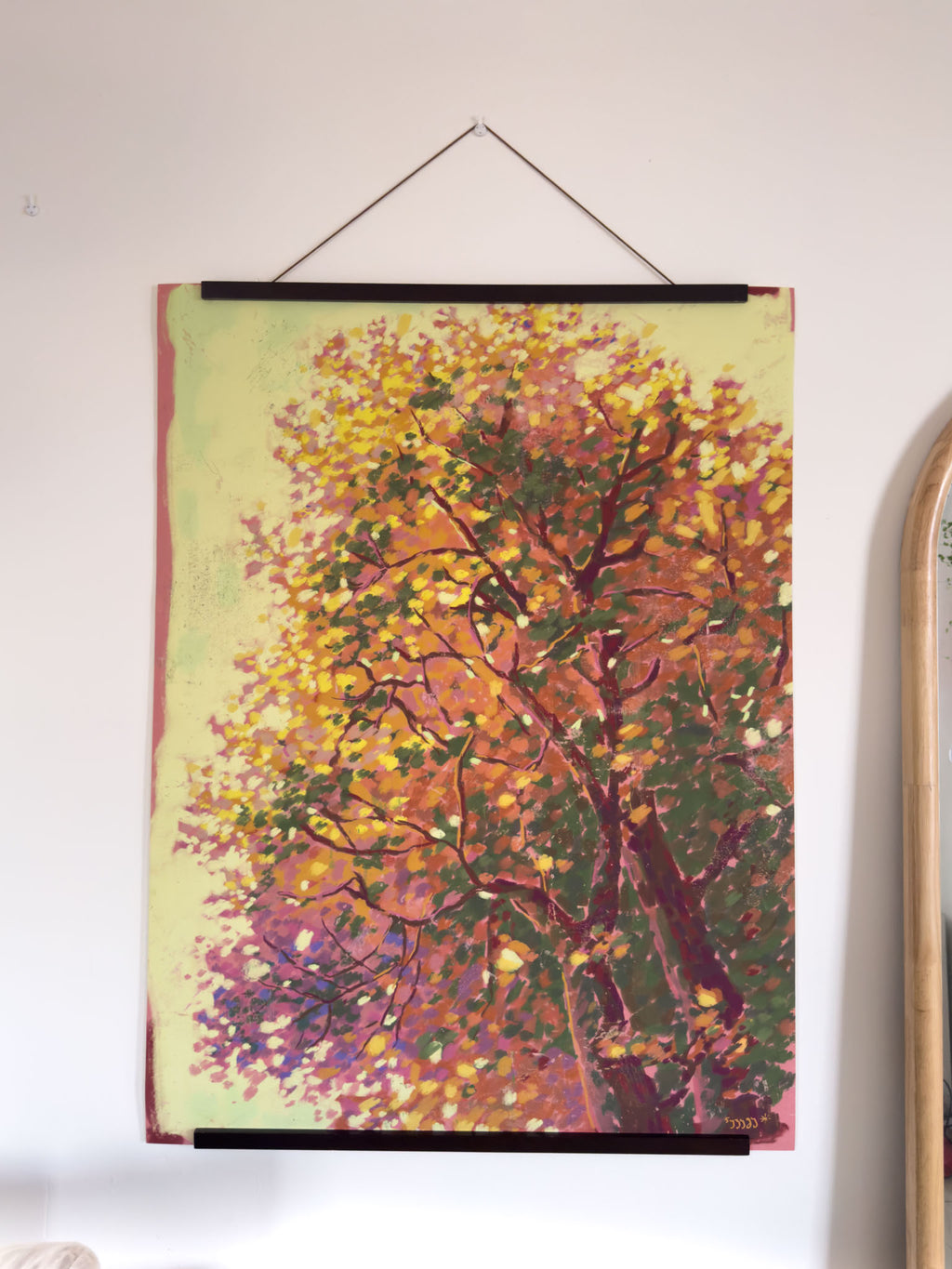 Framed painting of a tree with autumn foliage on a white wall.