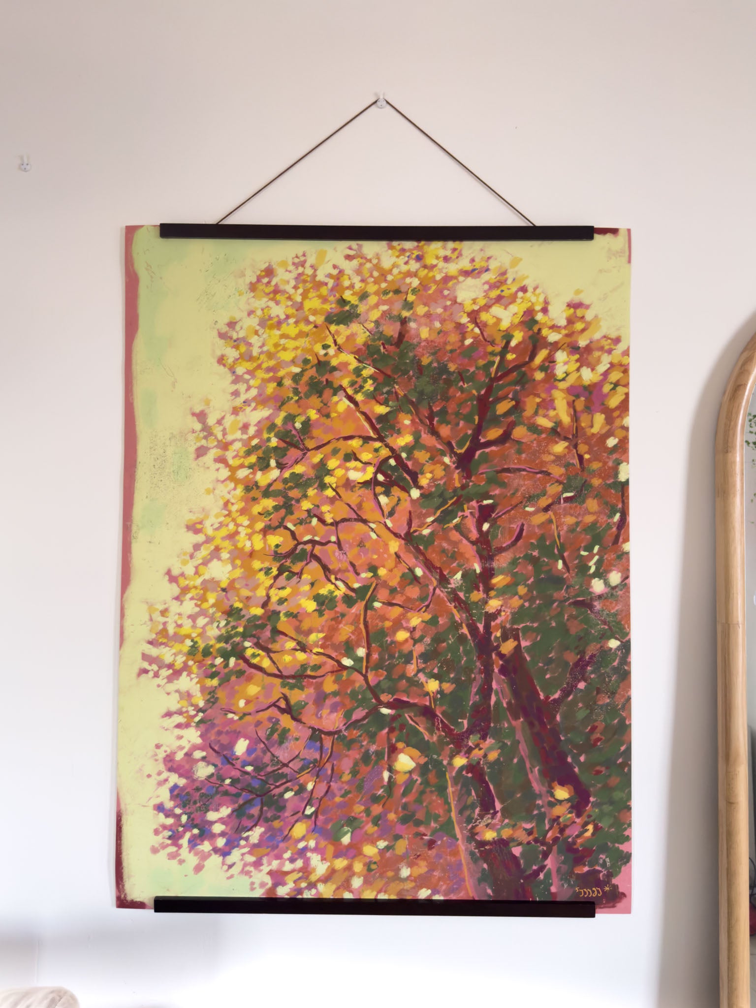 Framed painting of a tree with autumn foliage on a white wall.