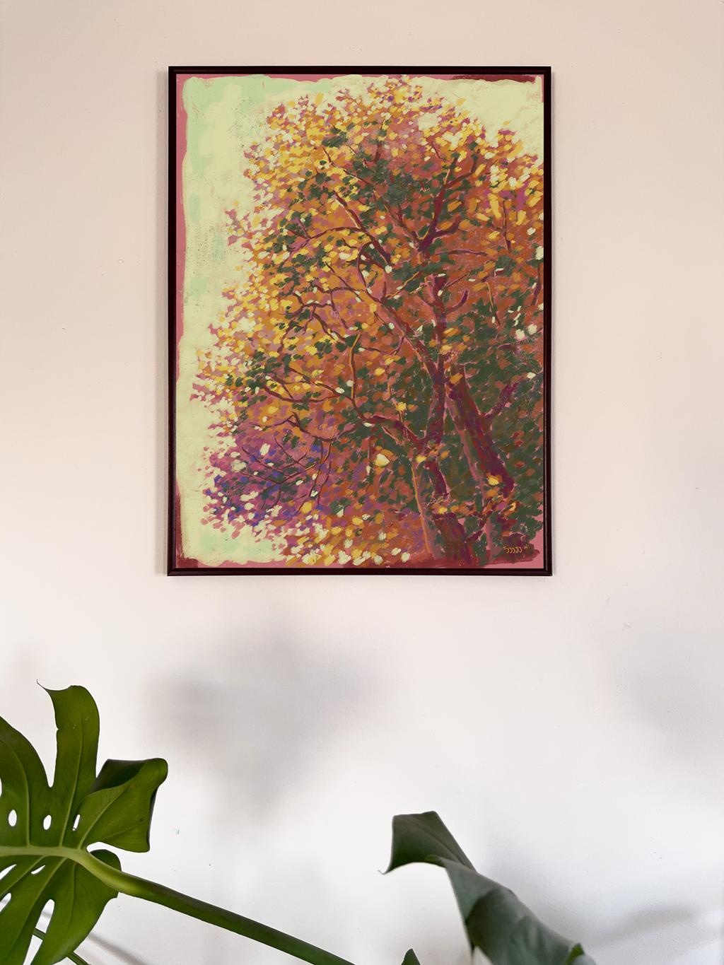 Framed artwork of a tree with autumn colors on a white wall.