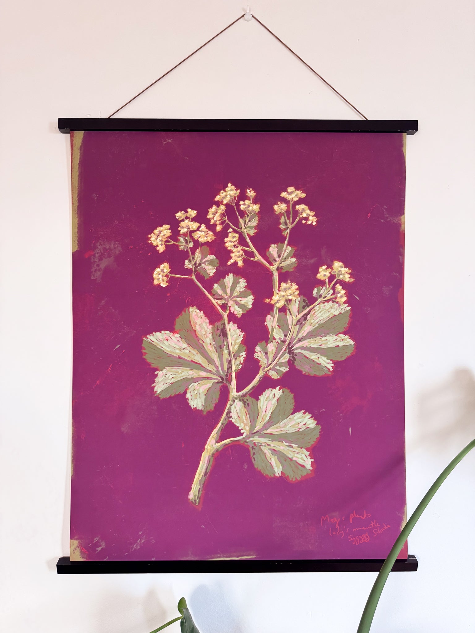 Floral print on a purple background with a black frame, hanging against a white wall.