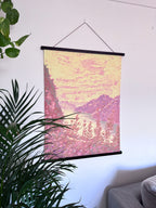 Wall art with hanger, with a pink and yellow abstract design hanging on a white wall.