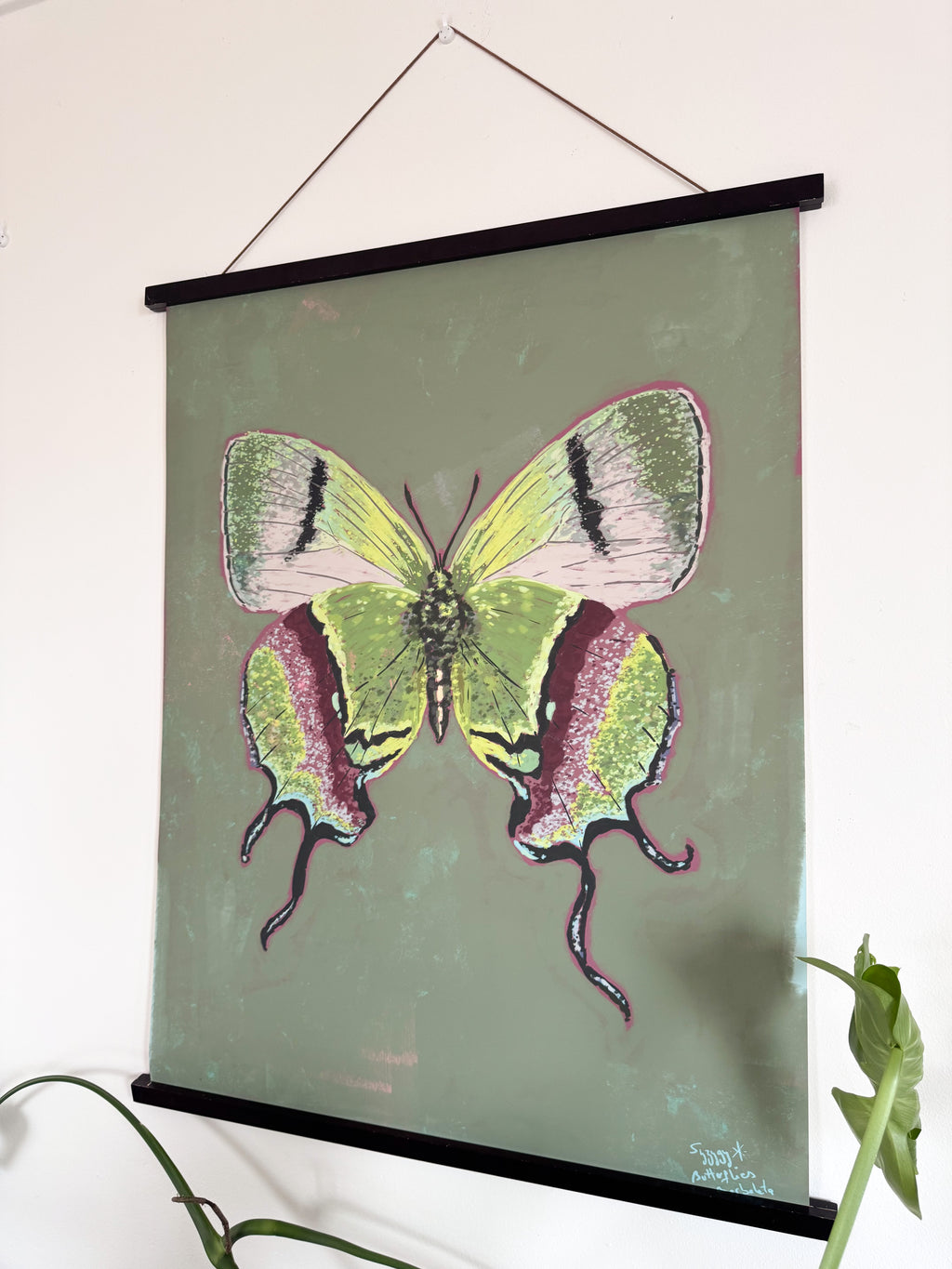 Butterfly illustration on a green background with a black frame, hanging on a wall.