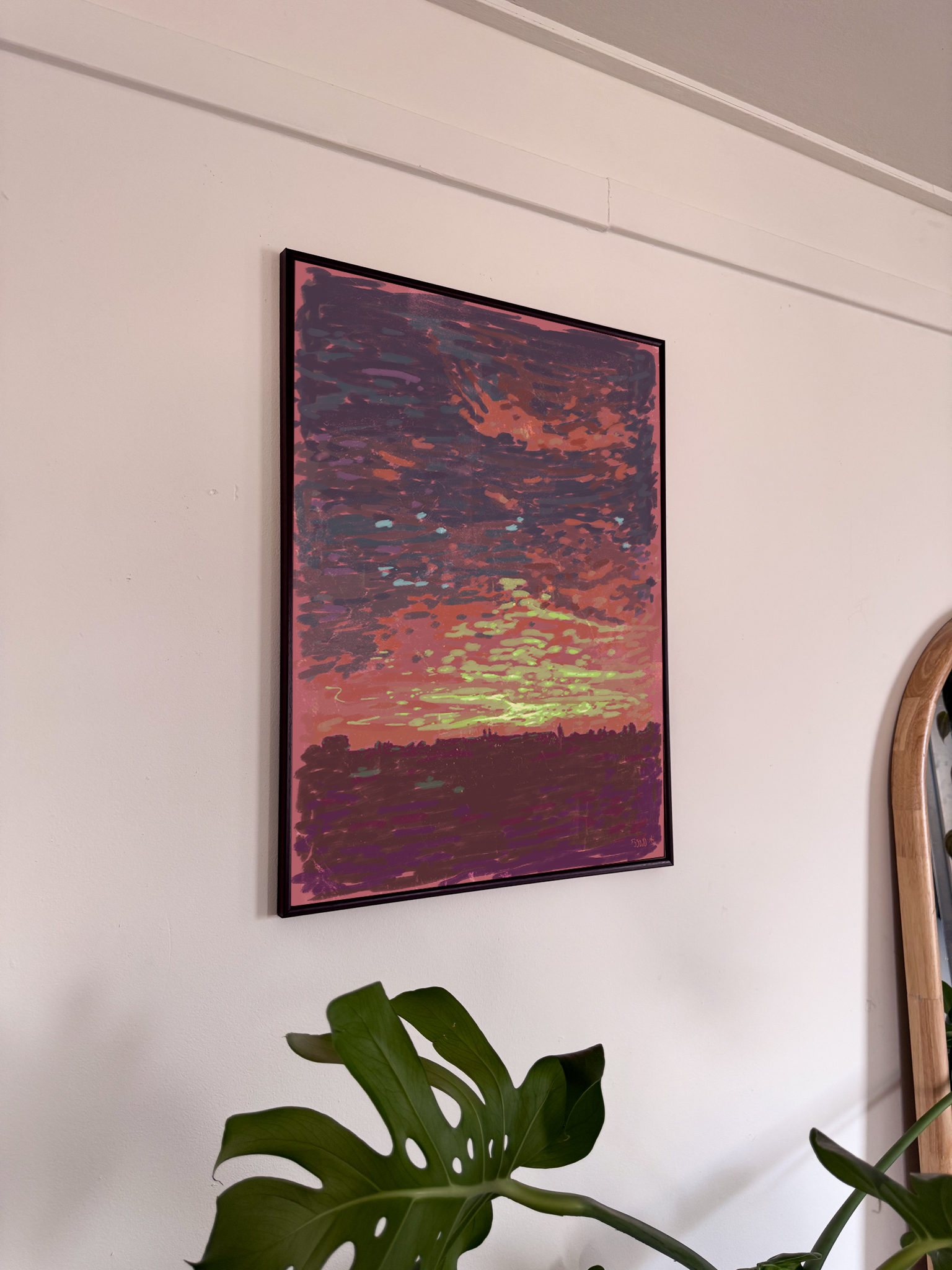 Framed impressionist artwork of a sunset on a wall with a plant in the foreground