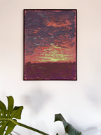 Framed abstract artwork with a sunset and landscape on a white wall.