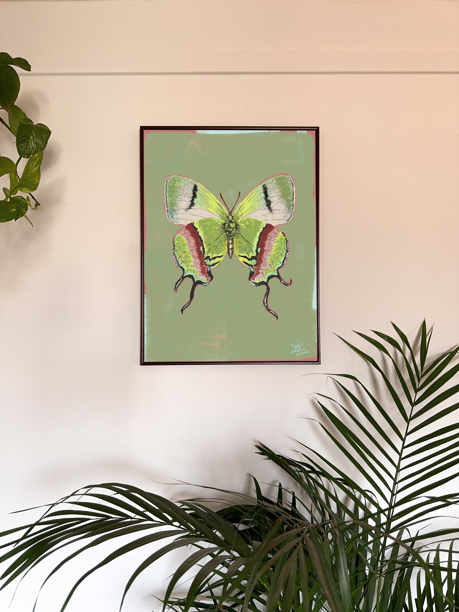 Framed artwork of a green butterfly on a light green background, surrounded by plants.