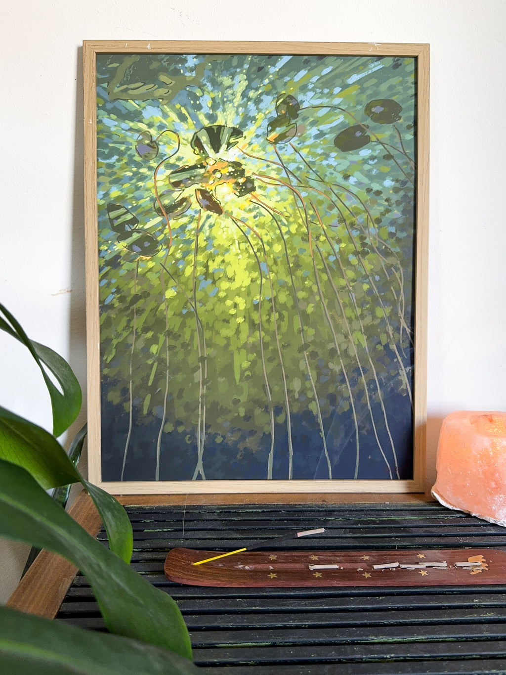 Impressionistic art print of a lake and lily pads in green colors on a wooden self