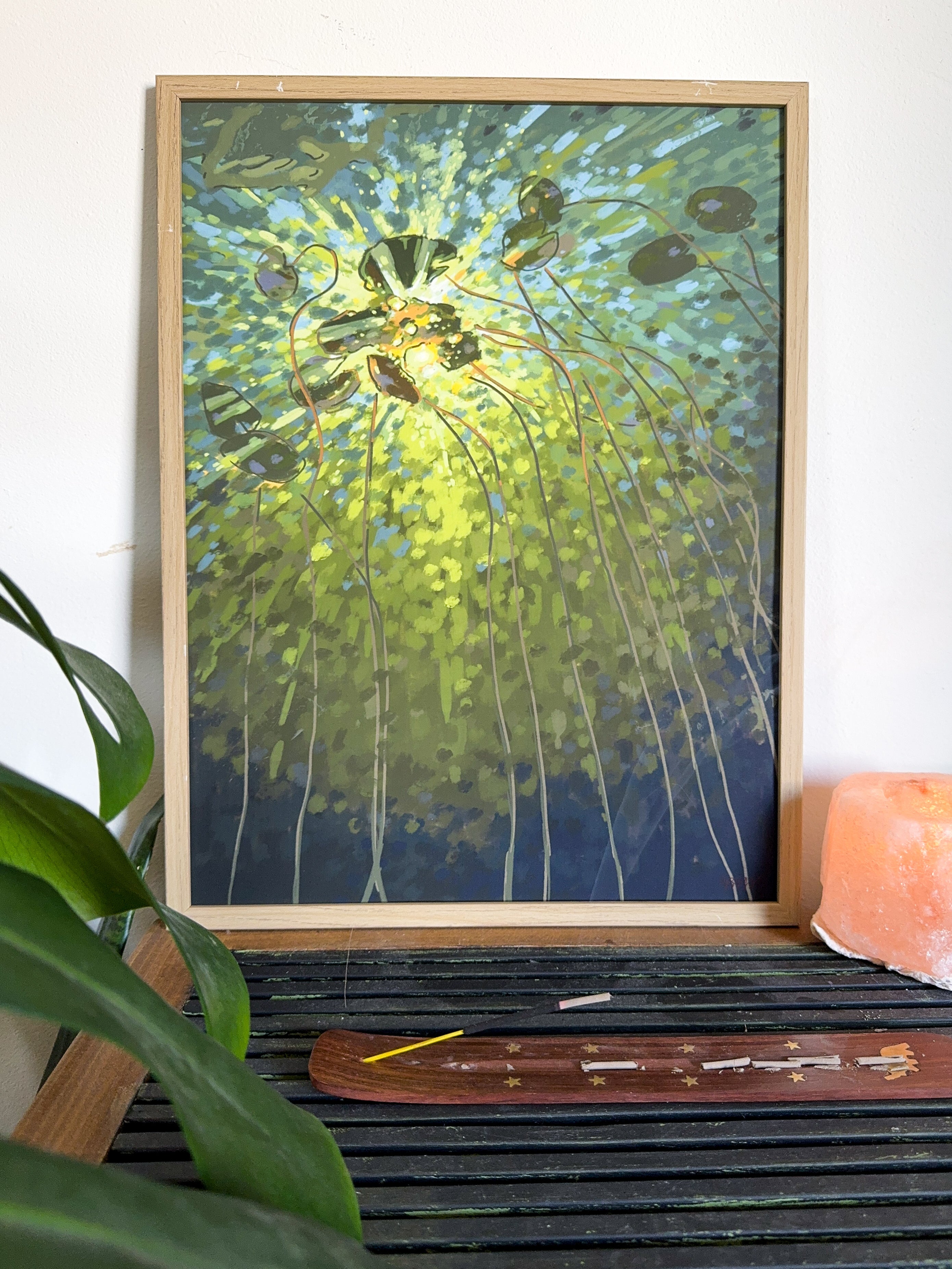 Impressionistic art print of a lake and lily pads in green colors on a wooden self