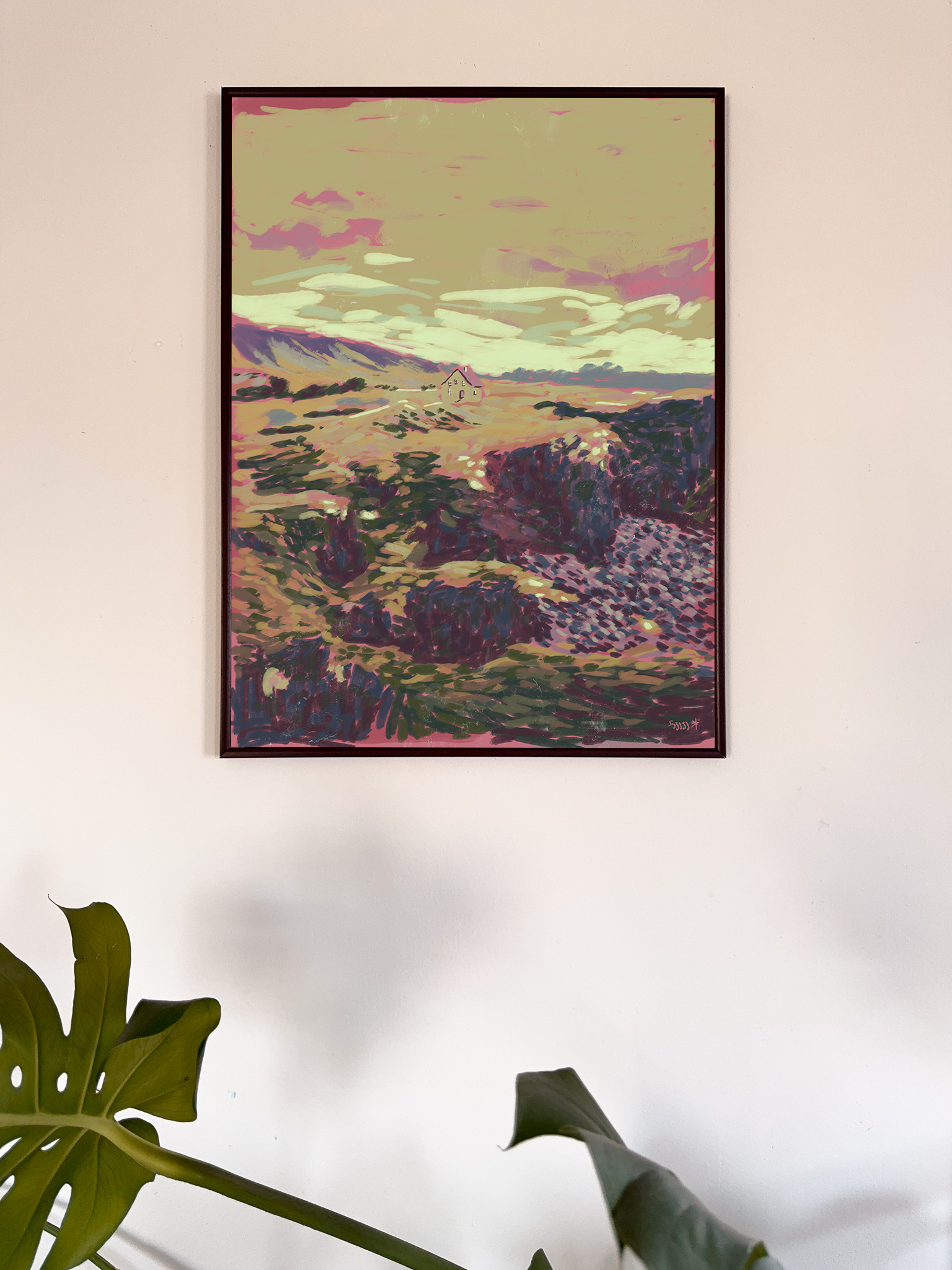 Framed artwork of a landscape with purple and green hues on a white wall.