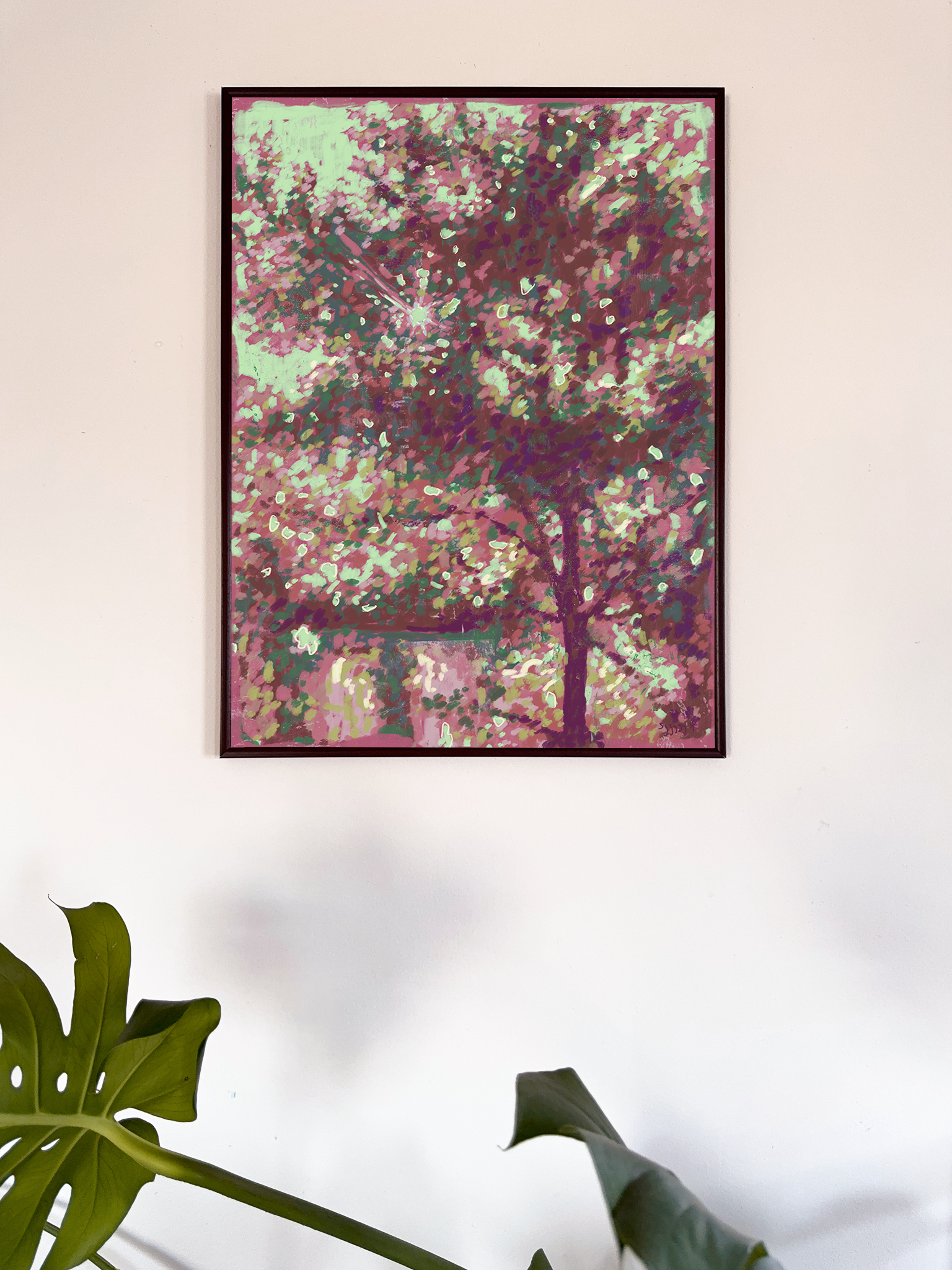 Framed abstract artwork with pink and green colors on a white wall.