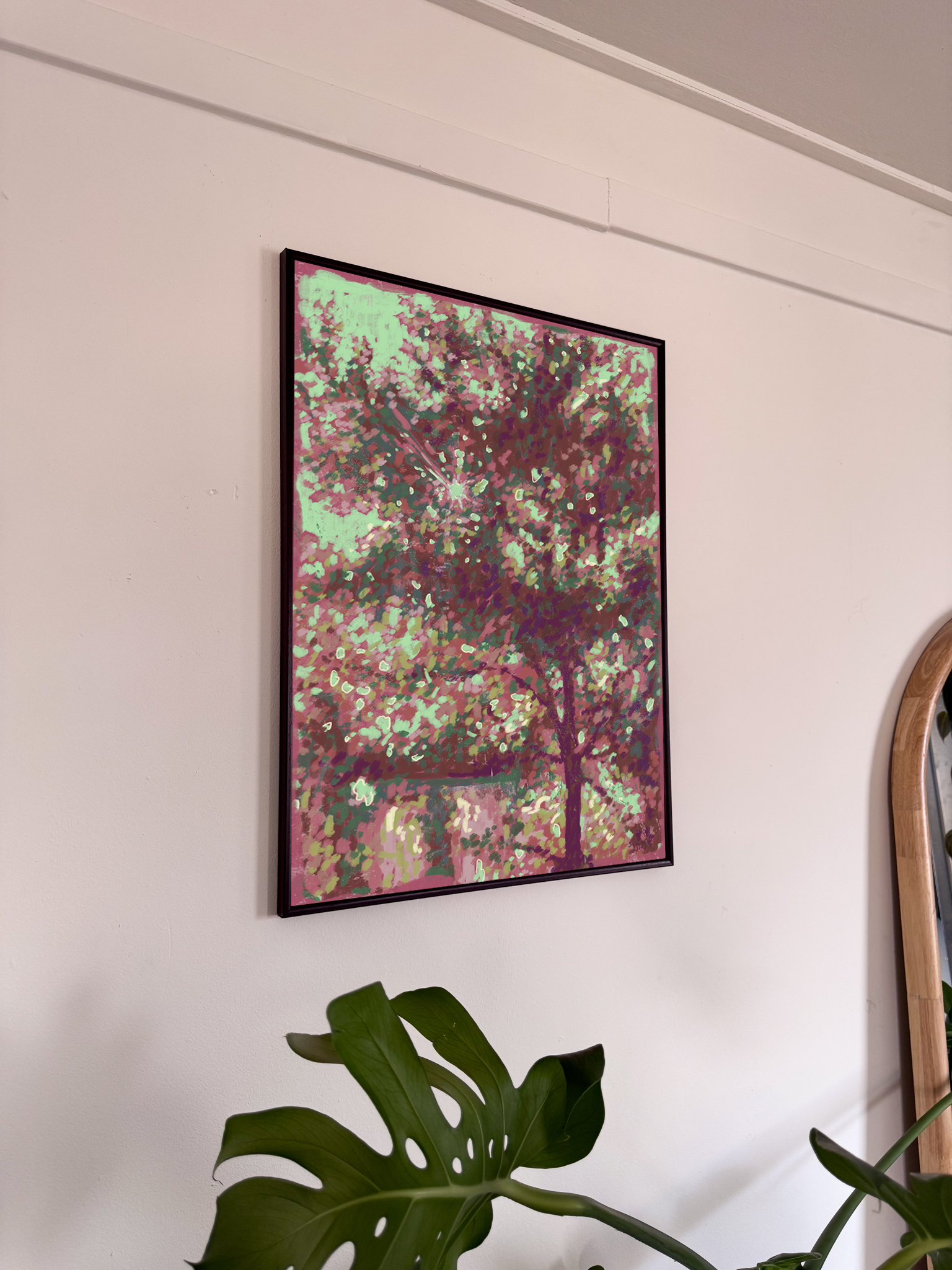 Framed abstract artwork on a wall with a plant in the foreground