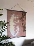 Wall art with a plant and mirror reflection hanging on a white wall.