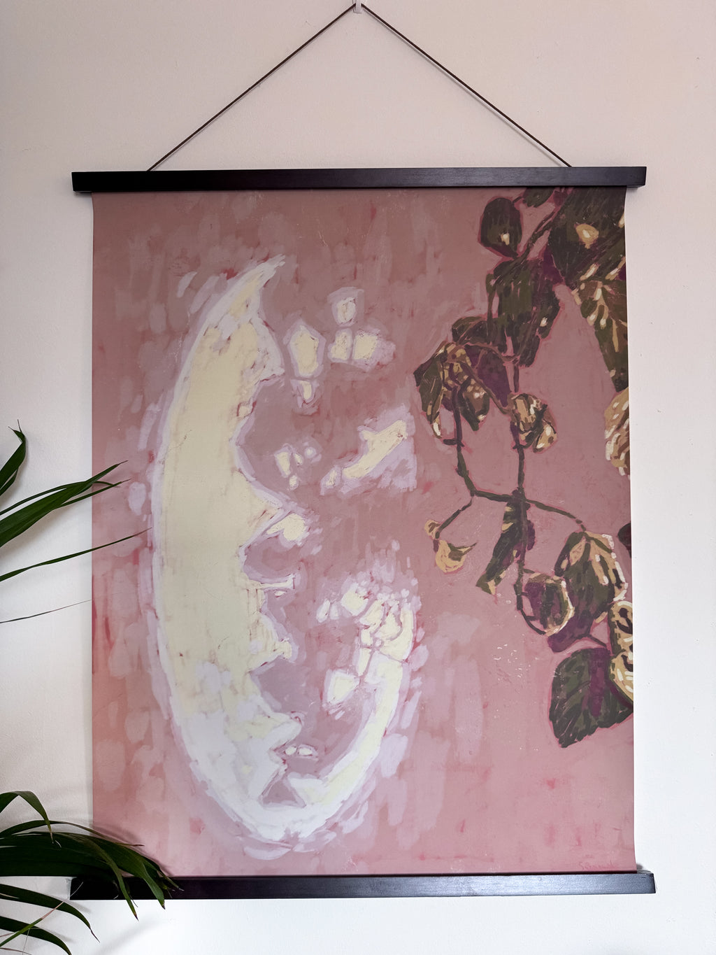 Wall art with plant design and moon-like shape reflection on a pink background