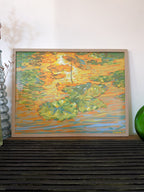 Framed impressionistic art print of a pond with lily pads with vibrant colors on a wooden shelf.