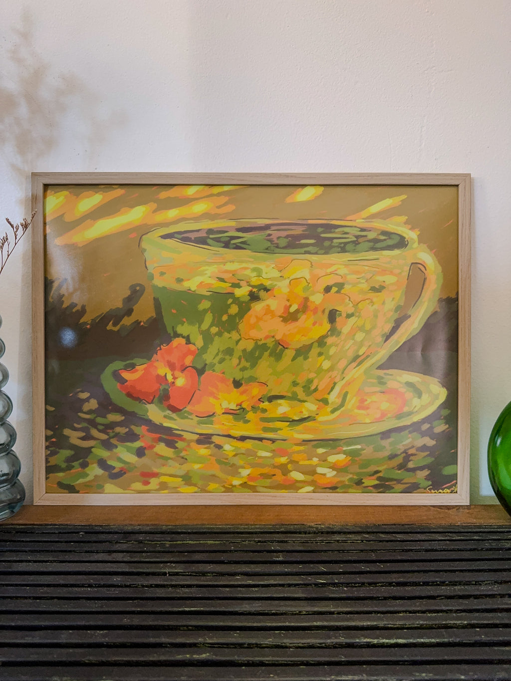 Framed painting of a teacup with flowers on a wooden surface