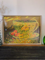 Framed painting of a teacup with flowers on a wooden surface