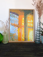 Framed impressionistic art print of sunbeams through a window, on a shelf with decorative vases and plants.