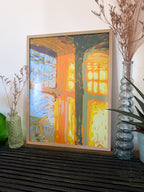 Framed impressionistic artwork of sunlight shinning through a window, on a shelf with decorative vases and plants.