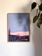 Framed artwork of a city sunset landscape with a tower on a white wall.