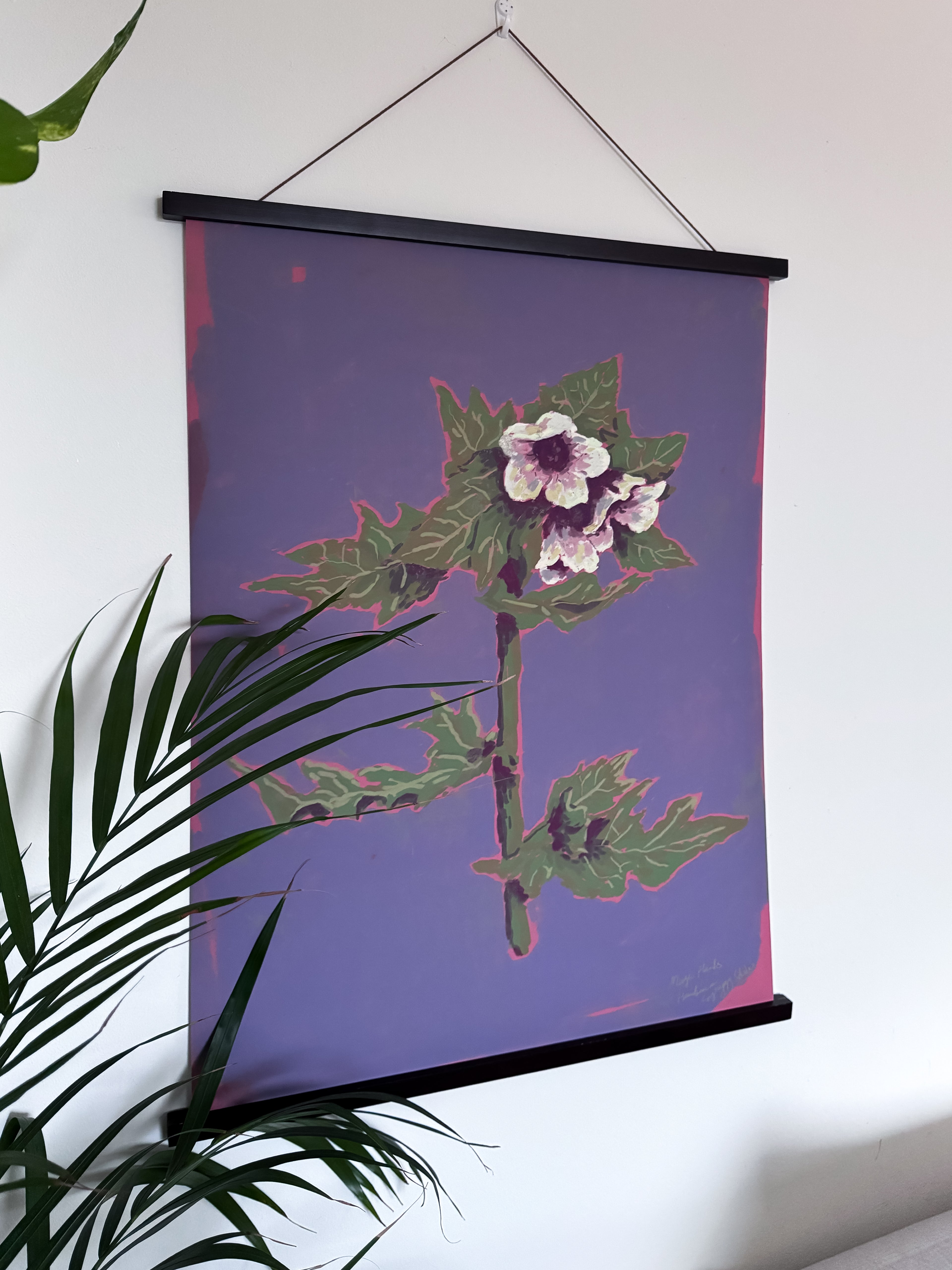 Floral henbane poster on a wall with green leaves in the foreground