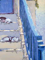 Two cats sleeping on a set of stairs with a blue railing.