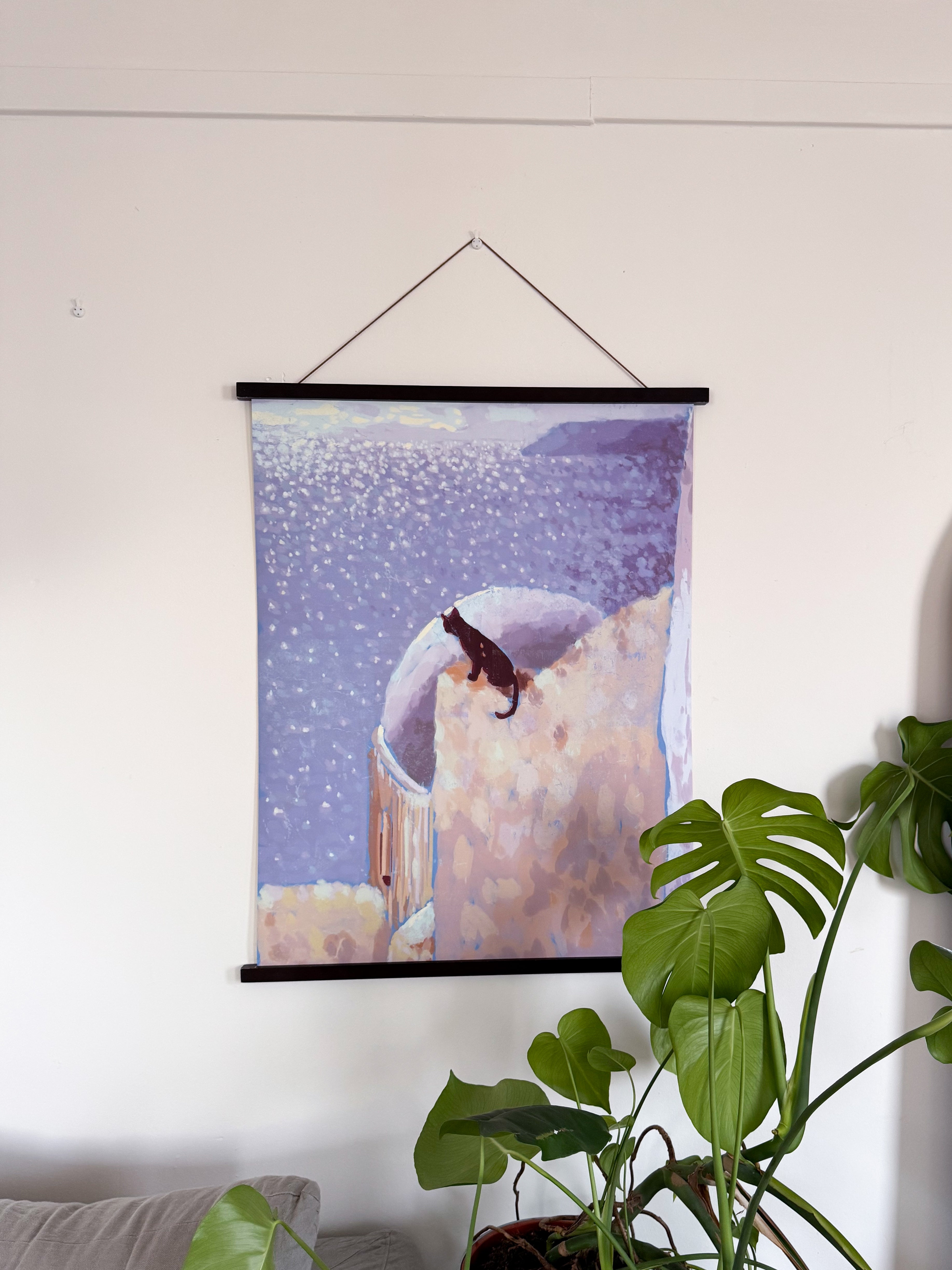 Framed artwork of a cat on a roof and the sea in the background