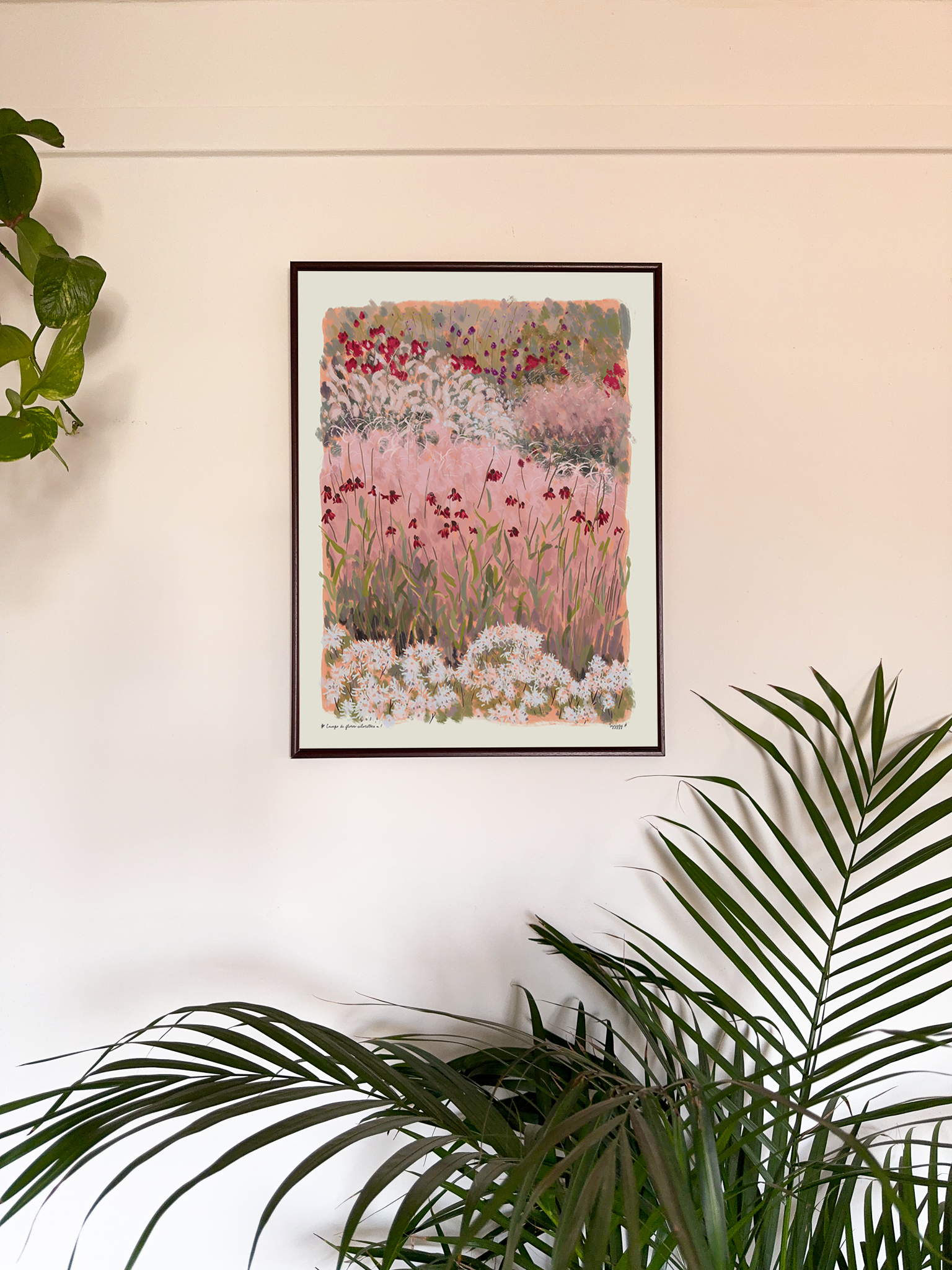 Framed floral artwork on a wall with plants in the foreground