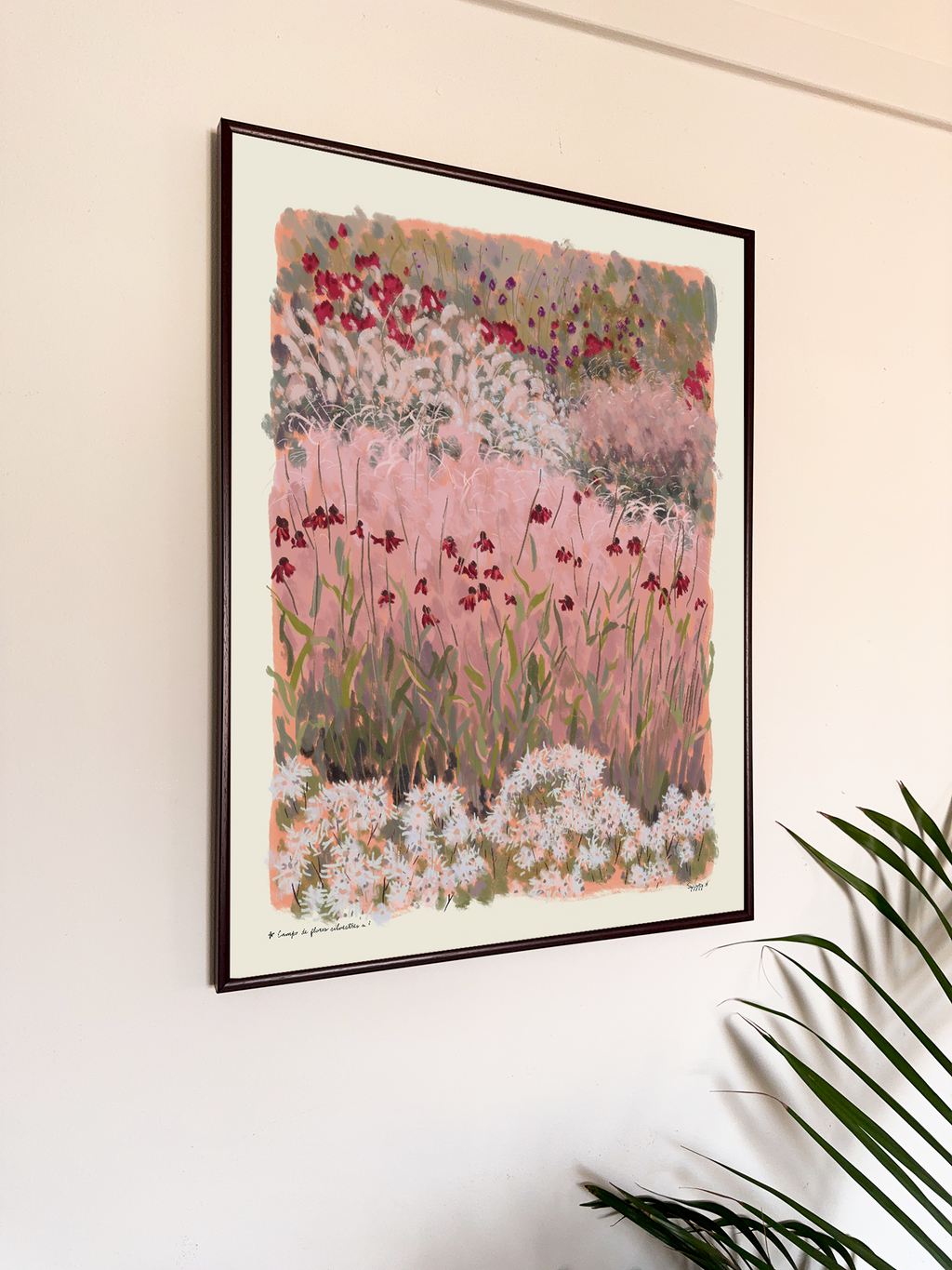 Framed artwork of a floral landscape on a wall with a plant in the foreground.