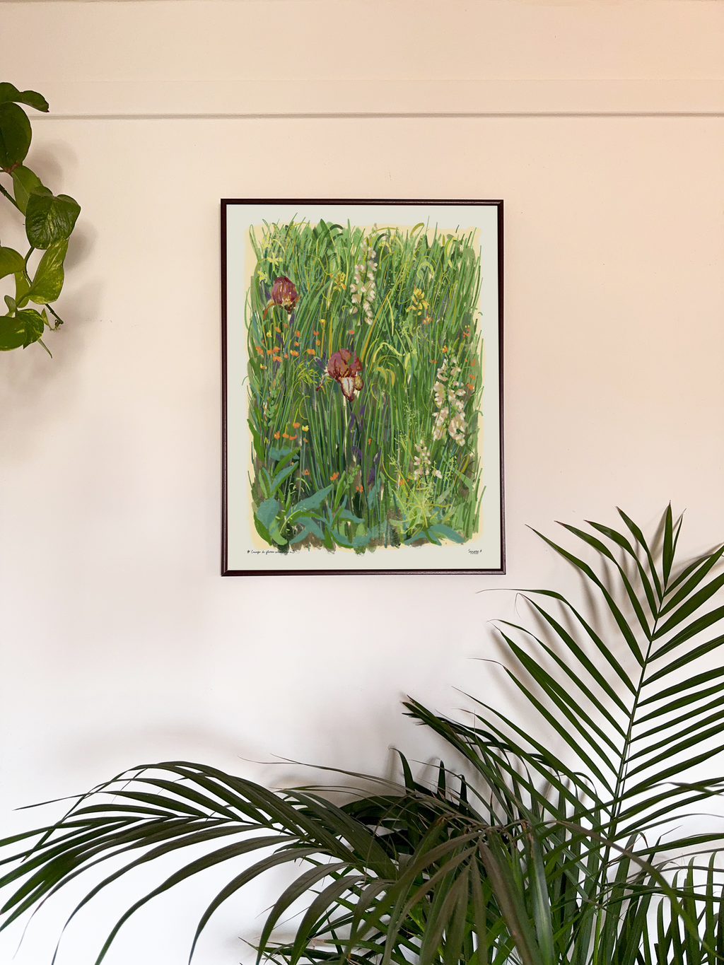 Framed artwork of a garden scene on a wall with plants around