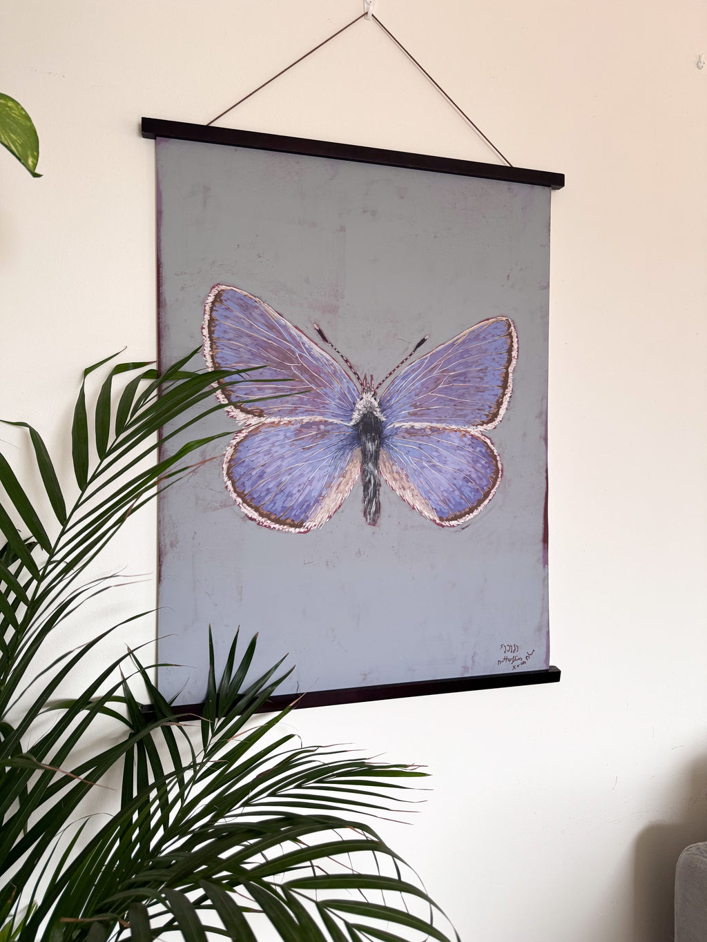 Butterfly illustration on a wall-mounted poster with green leaves in the foreground