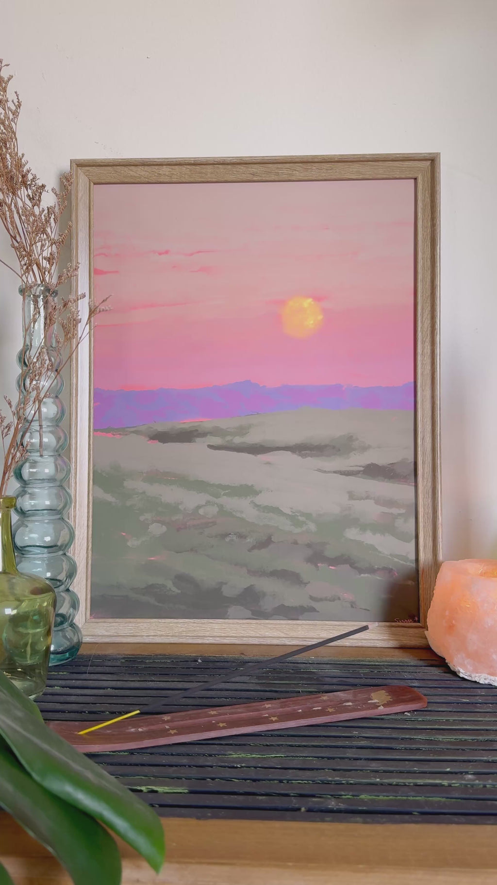 Video of an impressionistic art print of the moon with pink sky and a field