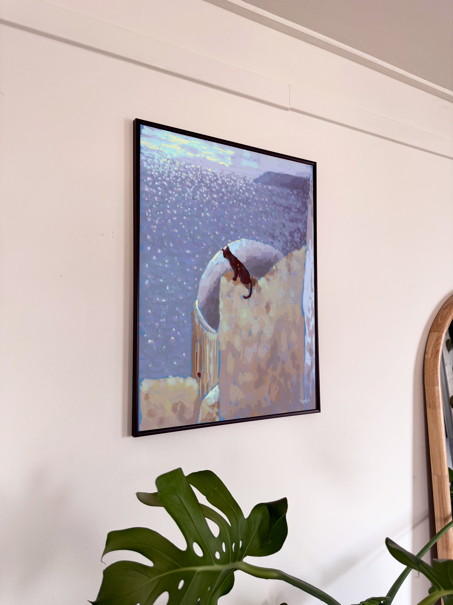 Framed artwork of a cat on a wall with a plant in the foreground
